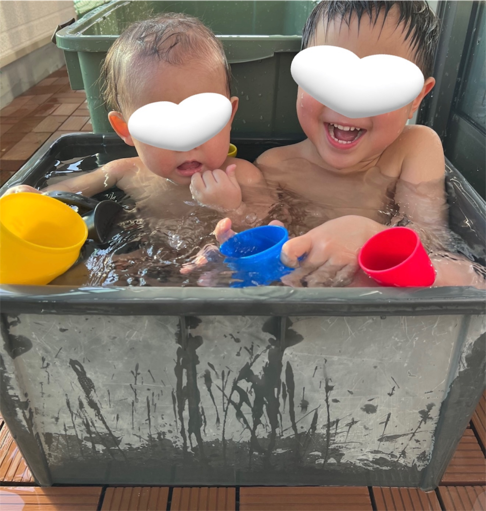 収納ボックスを露天風呂にして遊ぶ子ども2人