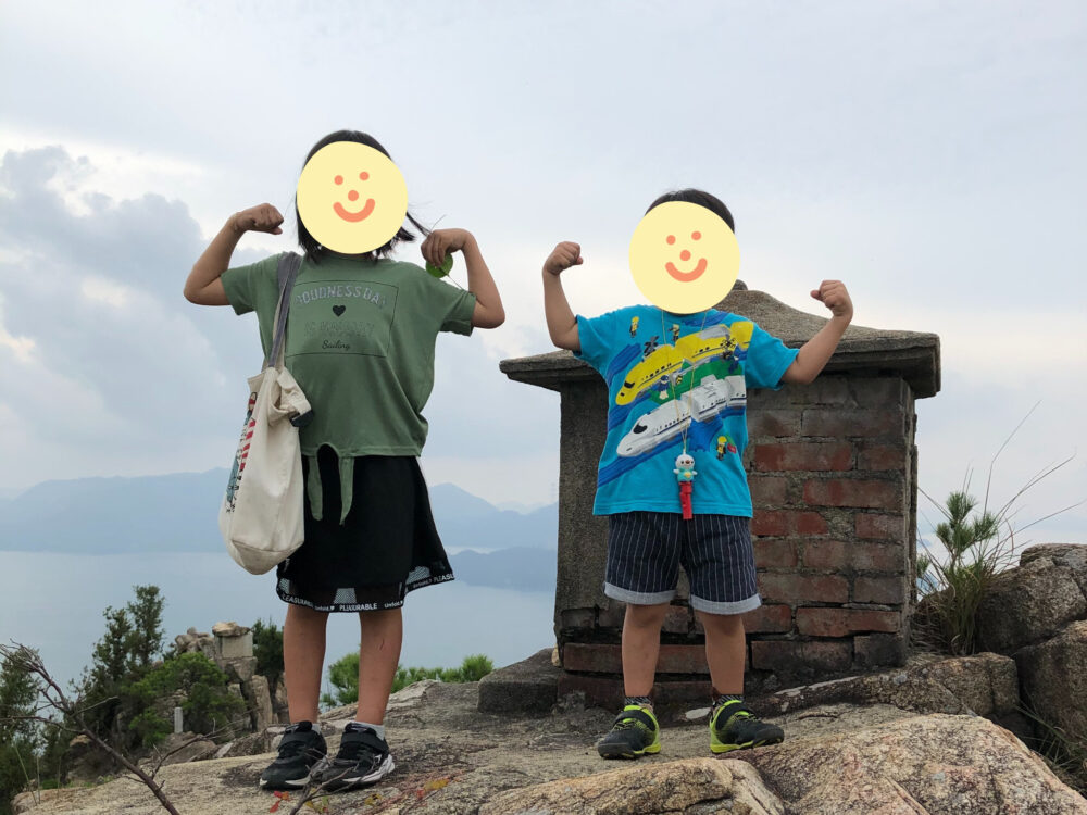 山頂でガッツポーズをする子どもたち